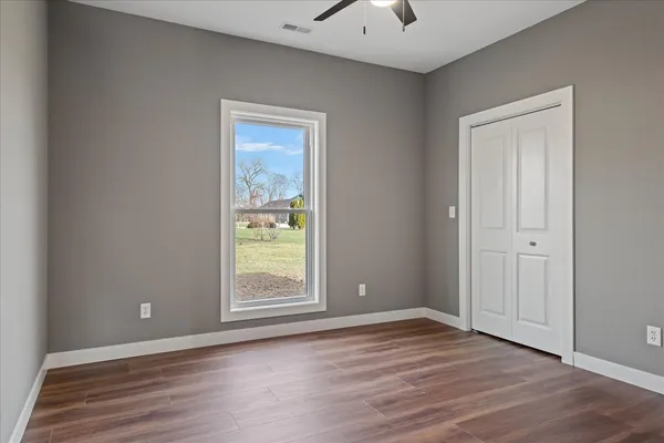 a view of an empty room with wooden floor and a window