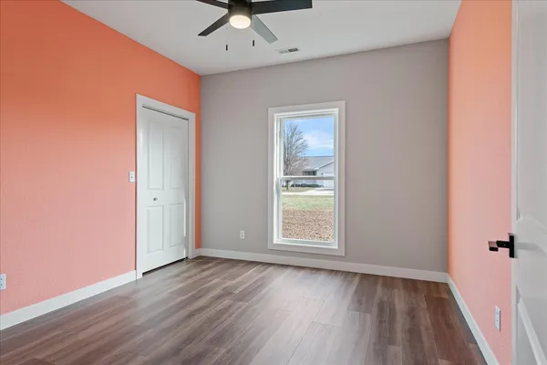 an empty room with a hardwood and ceiling fan