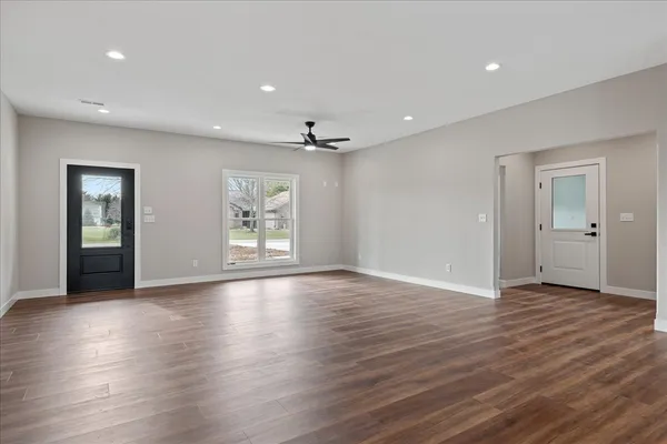 an empty room with wooden floor cabinet and windows