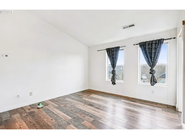 an empty room with wooden floor and window