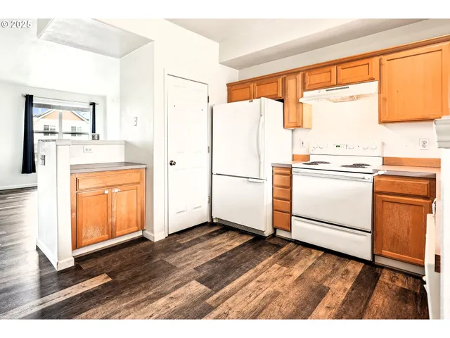 a kitchen with stainless steel appliances granite countertop a refrigerator a sink and white cabinets