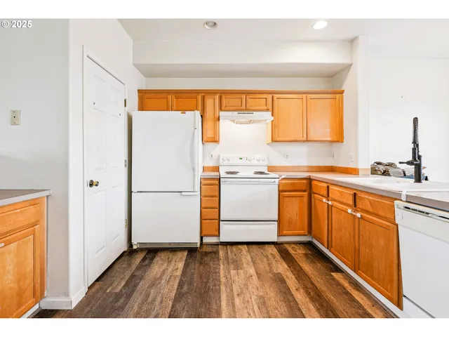 a kitchen with a refrigerator wooden floor a sink and a window