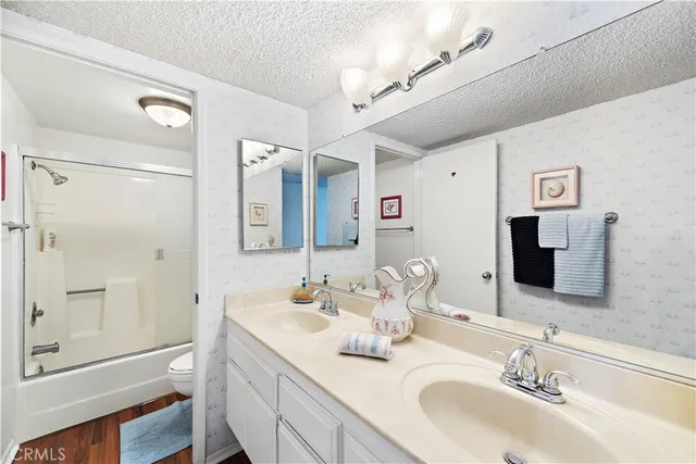 a bathroom with a granite countertop double vanity sink mirror and shower
