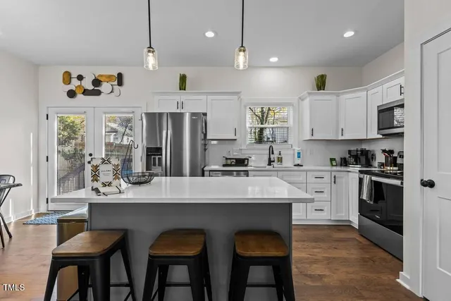 a kitchen with stainless steel appliances granite countertop a table chairs sink refrigerator and cabinets