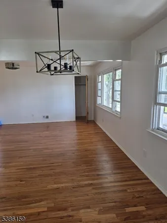 a view of a room with wooden floor chandelier and windows