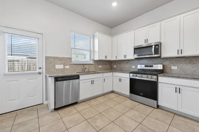 a kitchen with granite countertop white cabinets and appliances