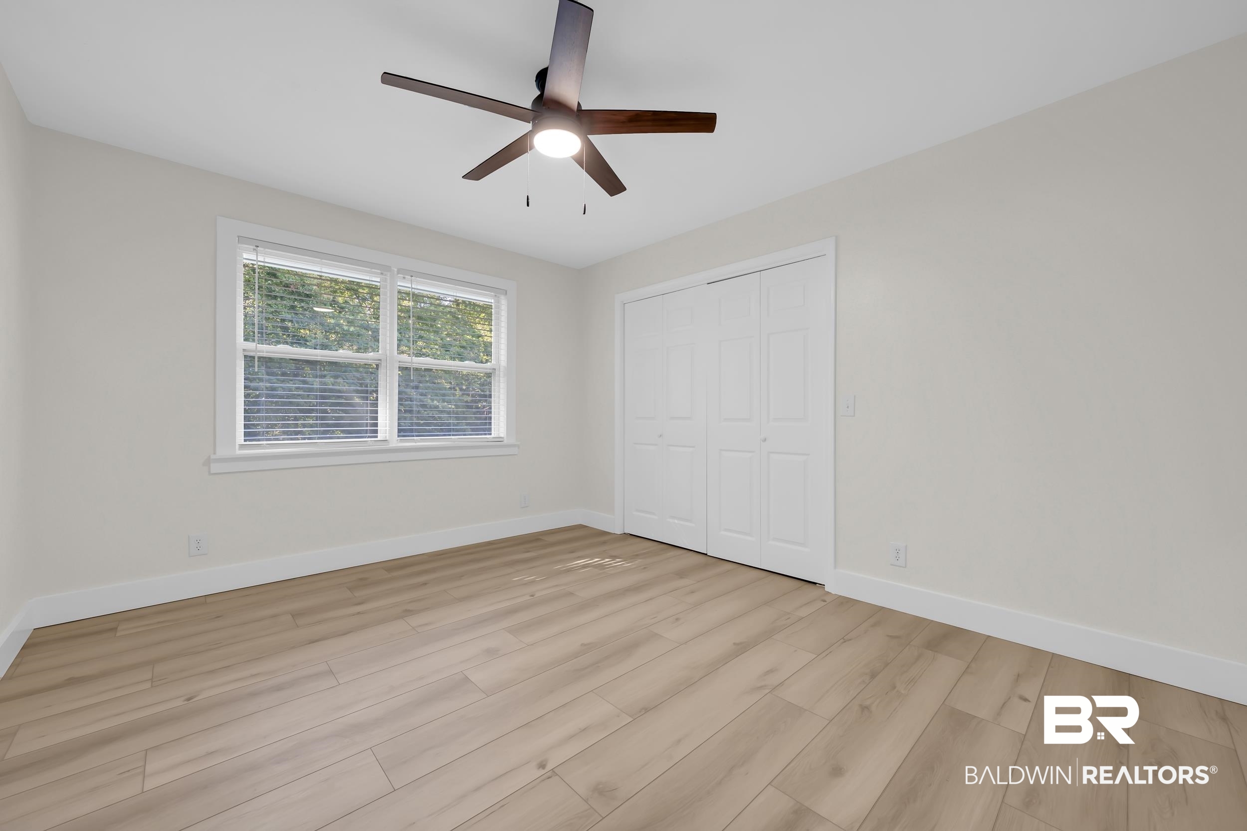 8170 Wilmer Georgetown Road Wilmer, AL 36587 - Photo 19 of 31 Bedroom featuring wood-finish flooring, a ceiling fan with integrated lighting, a double window with blinds, bi-fold closet doors, and light-toned wall paint
