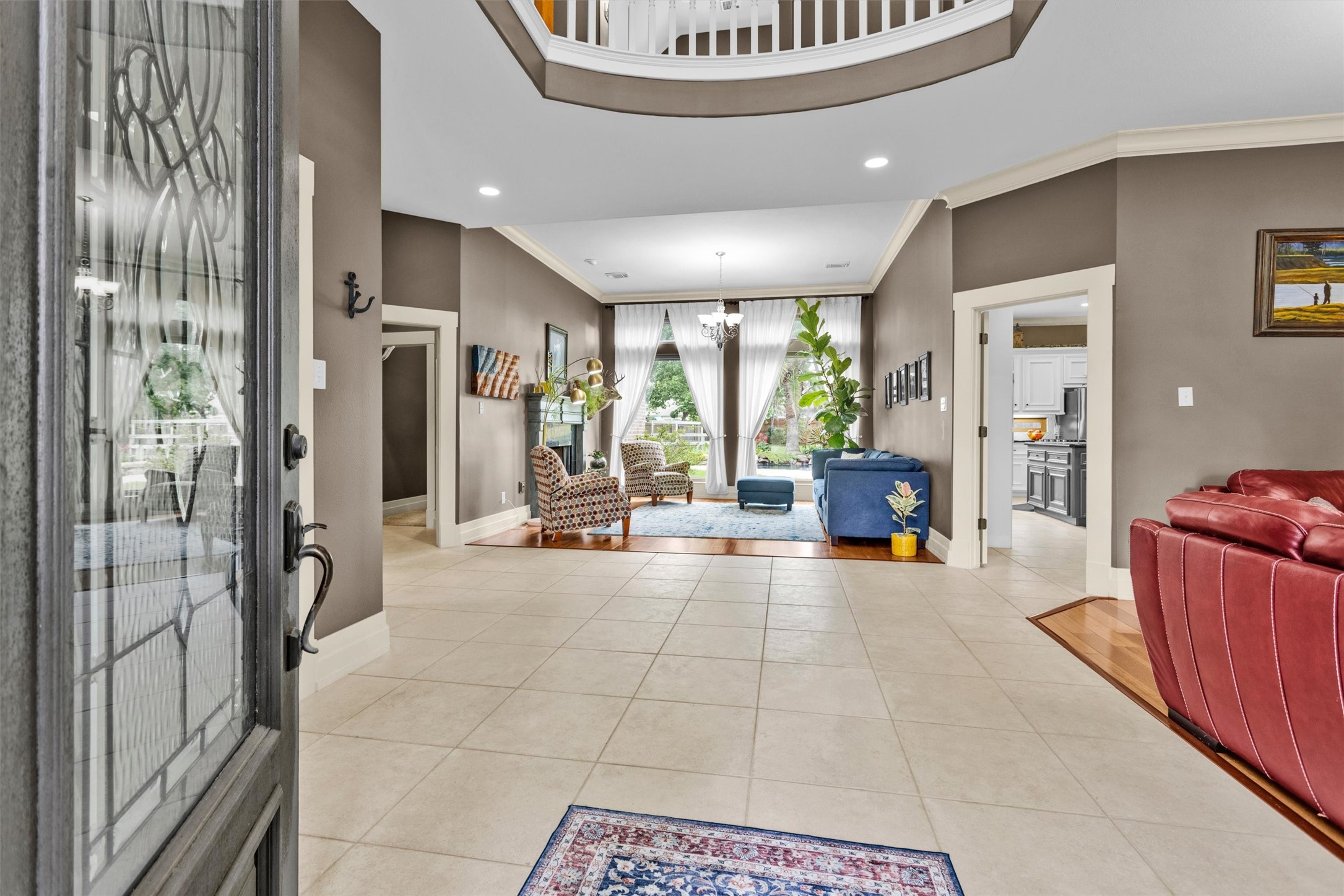 8314 Drew Haven Lane Spring, TX 77379 - Photo 5 of 49 The light-filled entryway and open layout leads to a cozy living area with large windows, and the adjacent kitchen is visible, offering a seamless flow for entertaining.