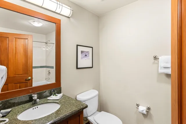 a bathroom with a granite countertop toilet sink and mirror
