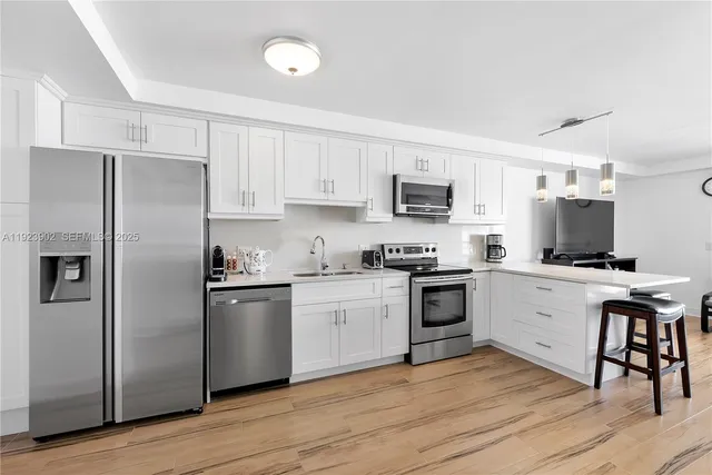 a kitchen with cabinets stainless steel appliances and wooden floor