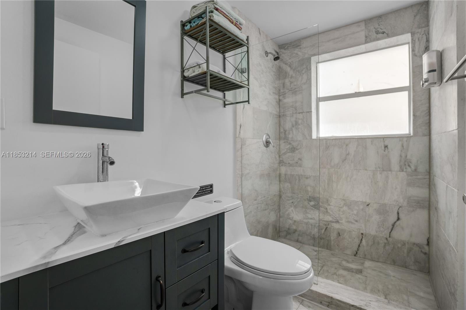 810 7th Street, Unit 107 Miami Beach, FL 33139 - Photo 19 of 36 a bathroom with a toilet a sink a mirror and a window