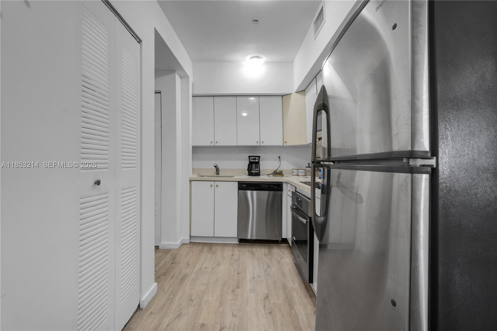 810 7th Street, Unit 107 Miami Beach, FL 33139 - Photo 9 of 36 a view of a kitchen with a sink and dishwasher a refrigerator with wooden floor