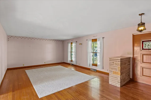 a view of an empty room with window and wooden floor