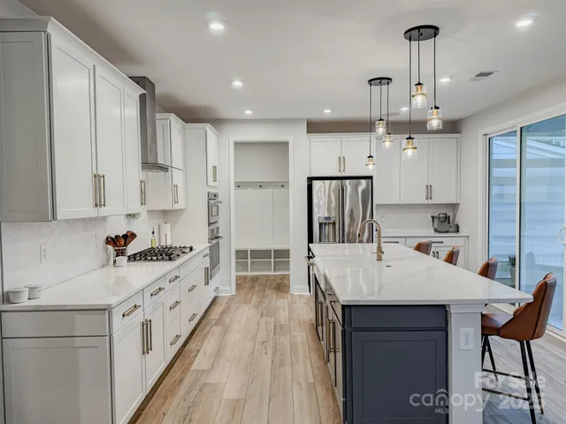 a kitchen with stainless steel appliances kitchen island granite countertop a sink refrigerator and cabinets