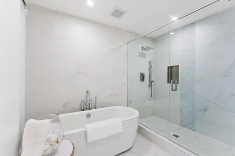 a bathroom with a white bath tub a mirror and a shower