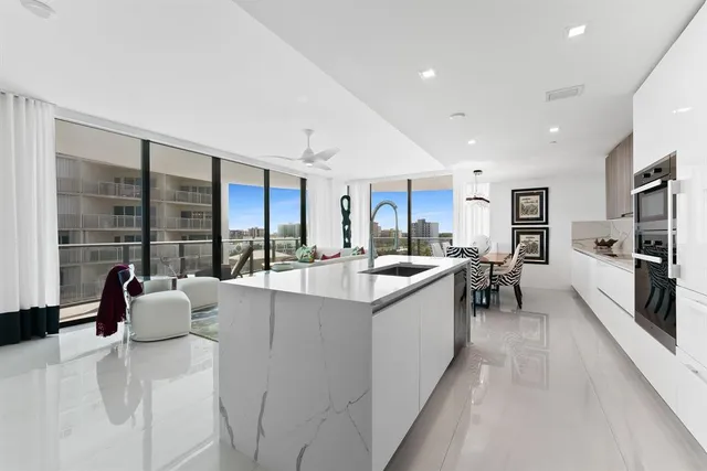 a large white kitchen with a large window and stainless steel appliances