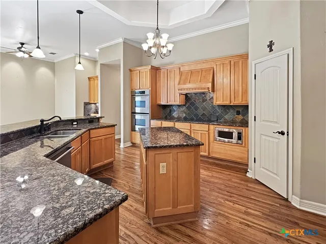 a large kitchen with granite countertop a sink a counter space and stainless steel appliances