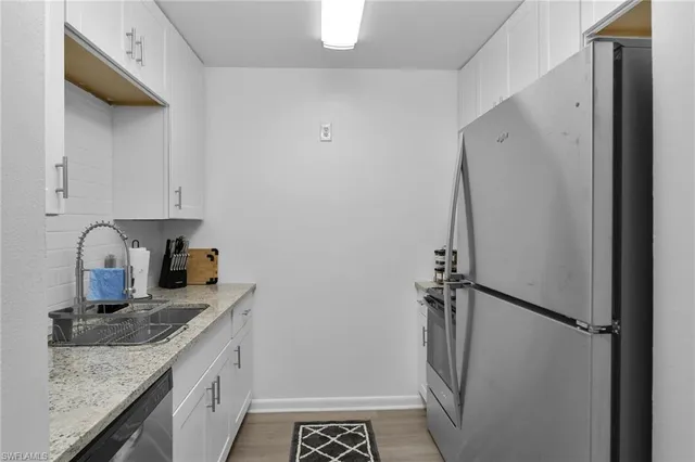 a kitchen with a granite countertop sink and refrigerator