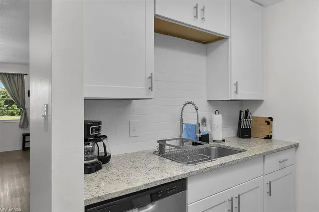 a kitchen with granite countertop a sink a stove and cabinets