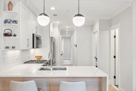a living room with furniture kitchen view and a chandelier