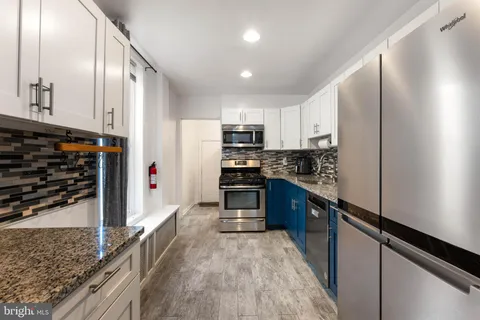 a kitchen with stainless steel appliances granite countertop a refrigerator a stove and a sink
