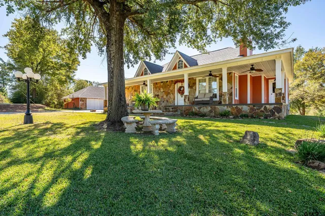 a view of a house with a yard patio and a tree
