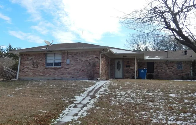 a front view of a building with a large tree