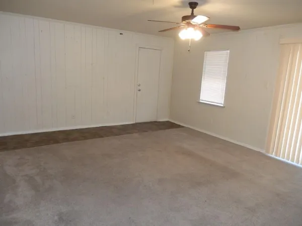 an empty room with a window and chandelier fan