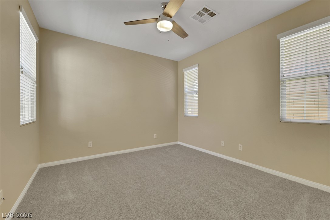 10328 Hawk Ravine Street Las Vegas, NV 89178 - Photo 20 of 55 A well-lit bedroom features plush carpeting and a modern ceiling fan, offering a comfortable personal retreat.