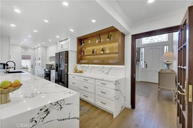 a kitchen with stainless steel appliances kitchen island granite countertop a refrigerator a sink a stove and oven with wooden floor