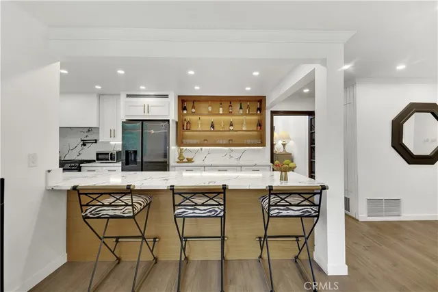 a kitchen with stainless steel appliances a dining table chairs and a refrigerator