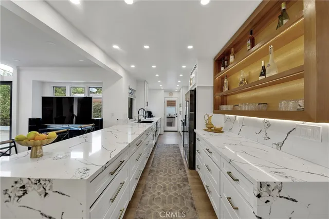 a large white kitchen with kitchen island a sink and a large window