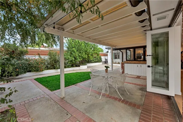a view of a patio with table and chairs potted plants with floor to ceiling window