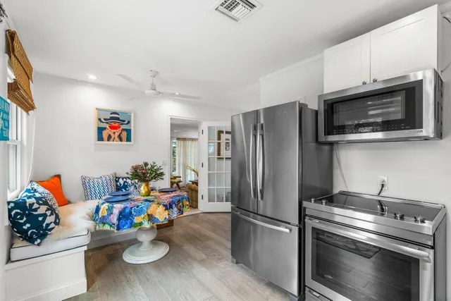 a kitchen with stainless steel appliances kitchen island granite countertop a refrigerator stove and white cabinets with wooden floor