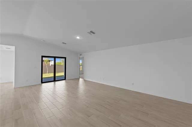 a view of an empty room with wooden floor and window