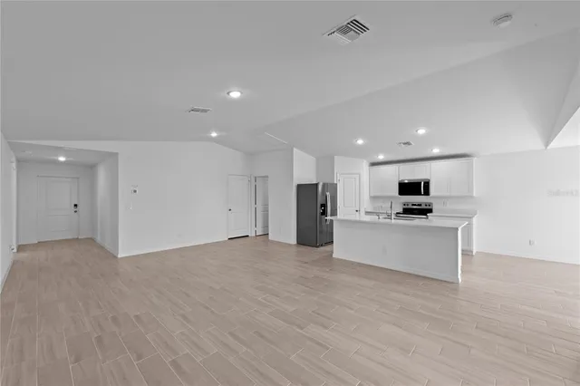a view of kitchen with kitchen island stainless steel appliances refrigerator stove microwave and cabinets