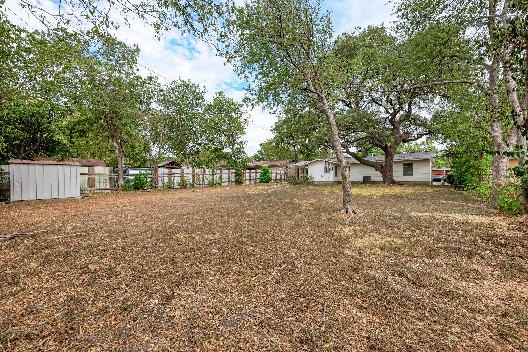 7804 Rutgers Avenue Austin, TX 78757 - Photo 23 of 32 Mature trees shade a spacious grassy area bordered by a full perimeter fence.