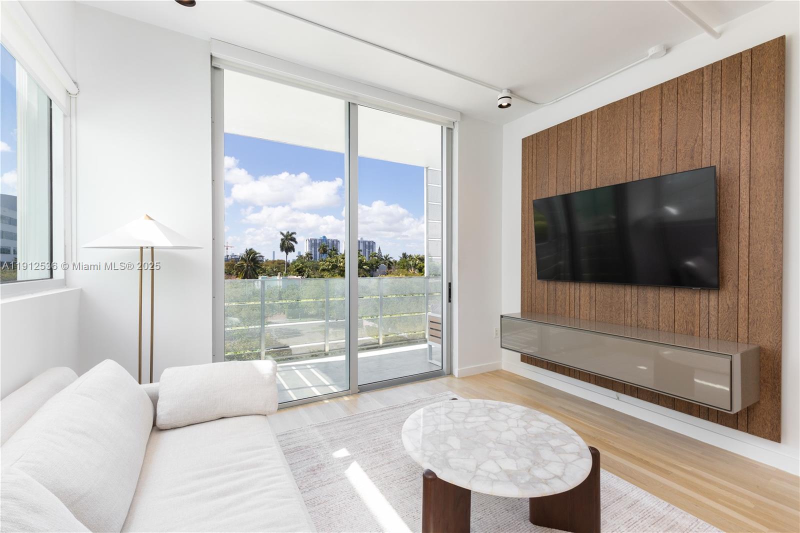 1700 Meridian Avenue, Unit 406 Miami Beach, FL 33139 - Photo 10 of 39 a living room with a large window and a flat screen tv