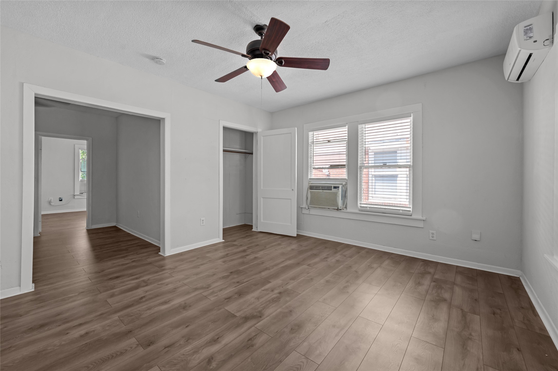 907 West Gray Street, Unit 4 Houston, TX 77019 - Photo 5 of 10 an empty room with wooden floor chandelier fan and windows