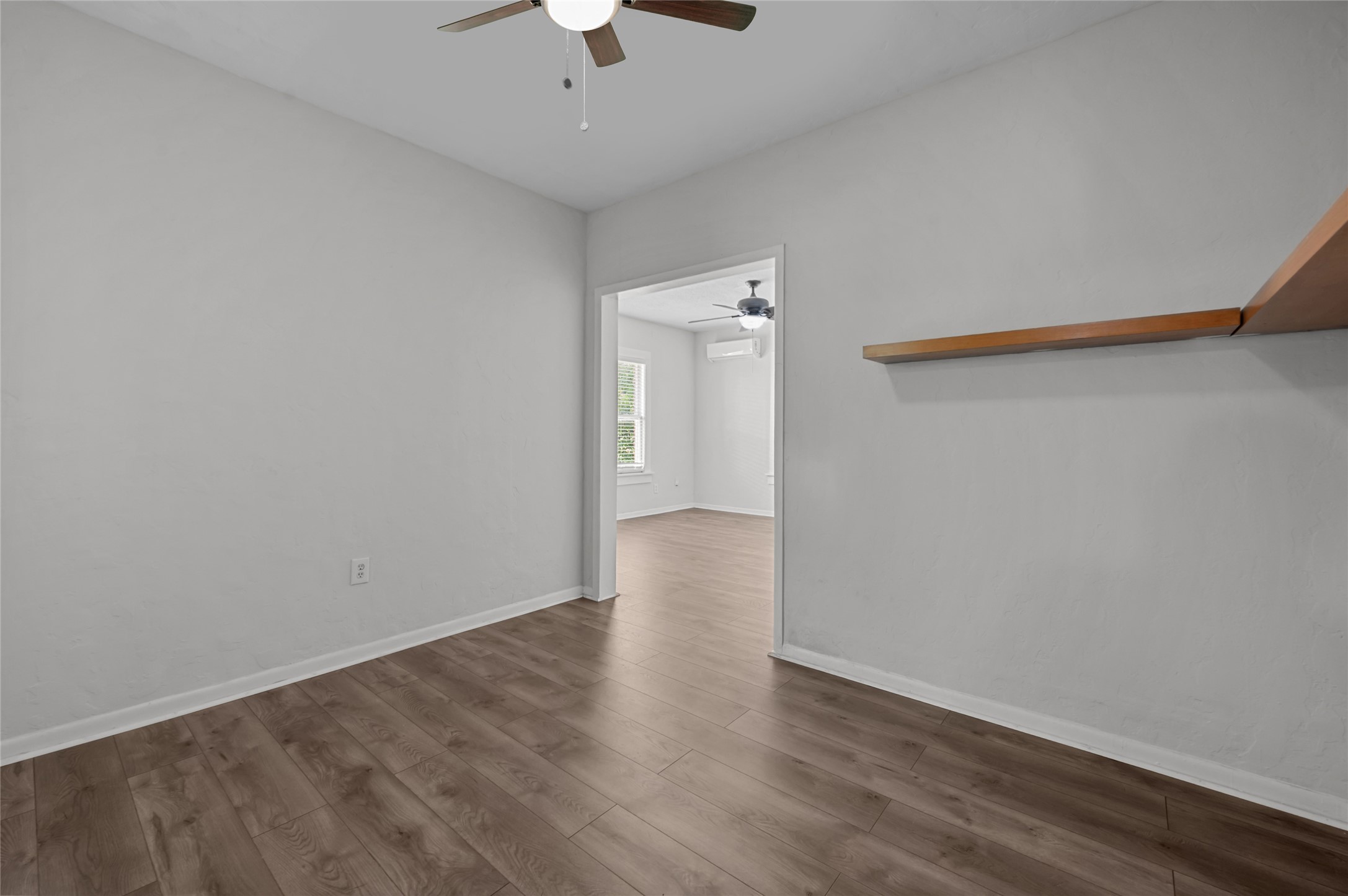 907 West Gray Street, Unit 4 Houston, TX 77019 - Photo 8 of 10 an empty room with wooden floor and chandelier fan