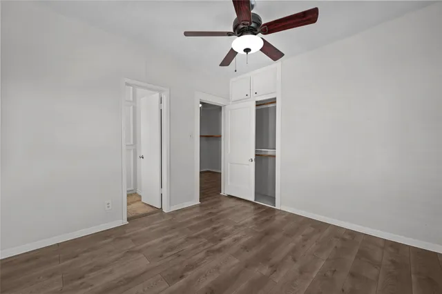 an empty room with wooden floor fan and windows