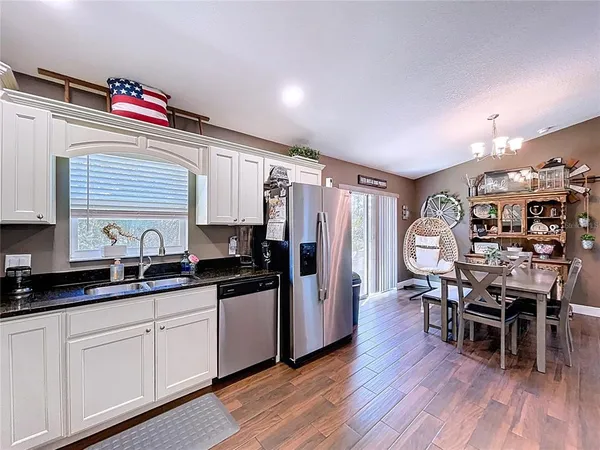 a kitchen with granite countertop a stove top oven a sink dishwasher a dining table and chairs with wooden floor