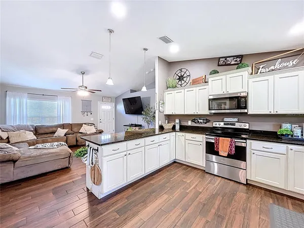 a kitchen with granite countertop a refrigerator and white cabinets