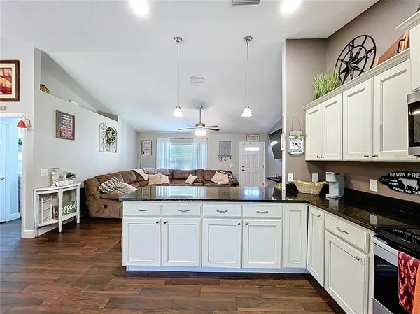 a kitchen with stainless steel appliances granite countertop a sink dishwasher a stove and white cabinets with wooden floor