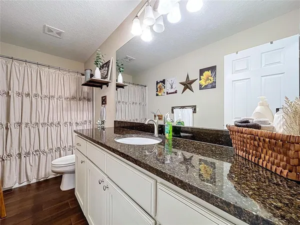 a bathroom with a granite countertop sink a toilet and a mirror