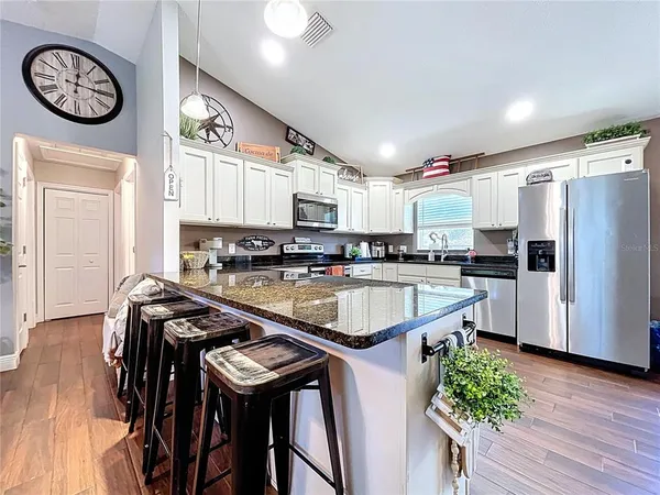 a kitchen with granite countertop a refrigerator and a stove top oven