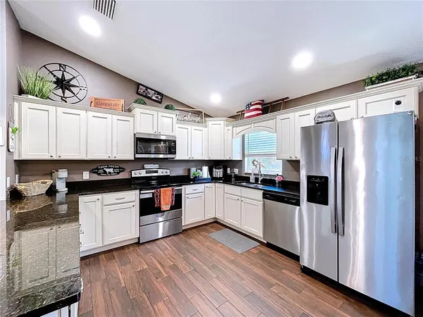 a kitchen with granite countertop kitchen island stainless steel appliances a dining table and chairs