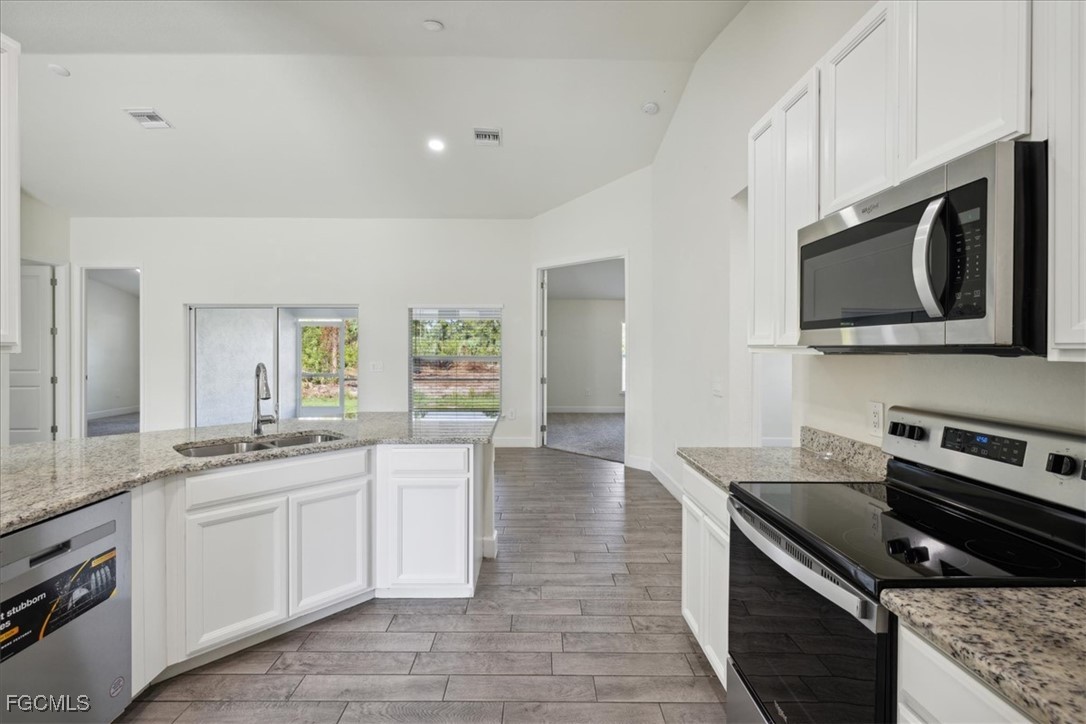 2914 Flora Avenue North Lehigh Acres, FL 33971 - Photo 13 of 39 a kitchen with stainless steel appliances a stove microwave and sink