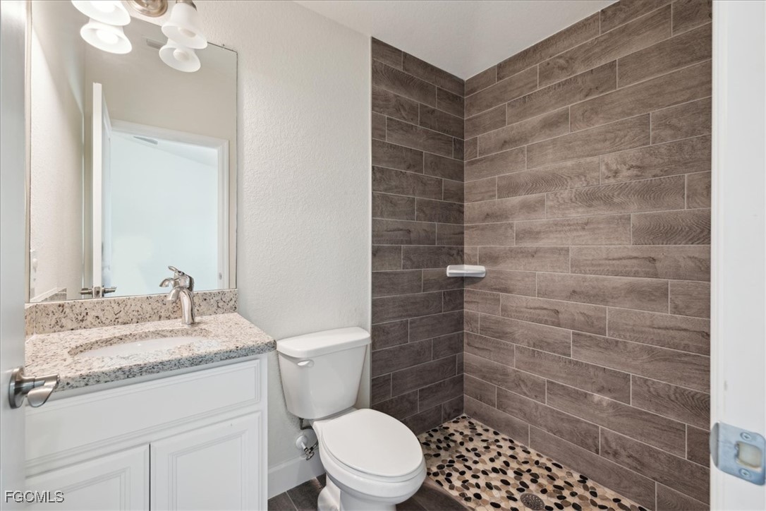 2914 Flora Avenue North Lehigh Acres, FL 33971 - Photo 20 of 39 a bathroom with a granite countertop toilet sink and mirror