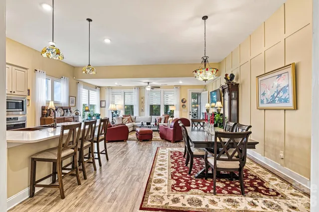 a kitchen with stainless steel appliances kitchen island granite countertop a refrigerator a stove top oven a sink dishwasher and white cabinets with wooden floor